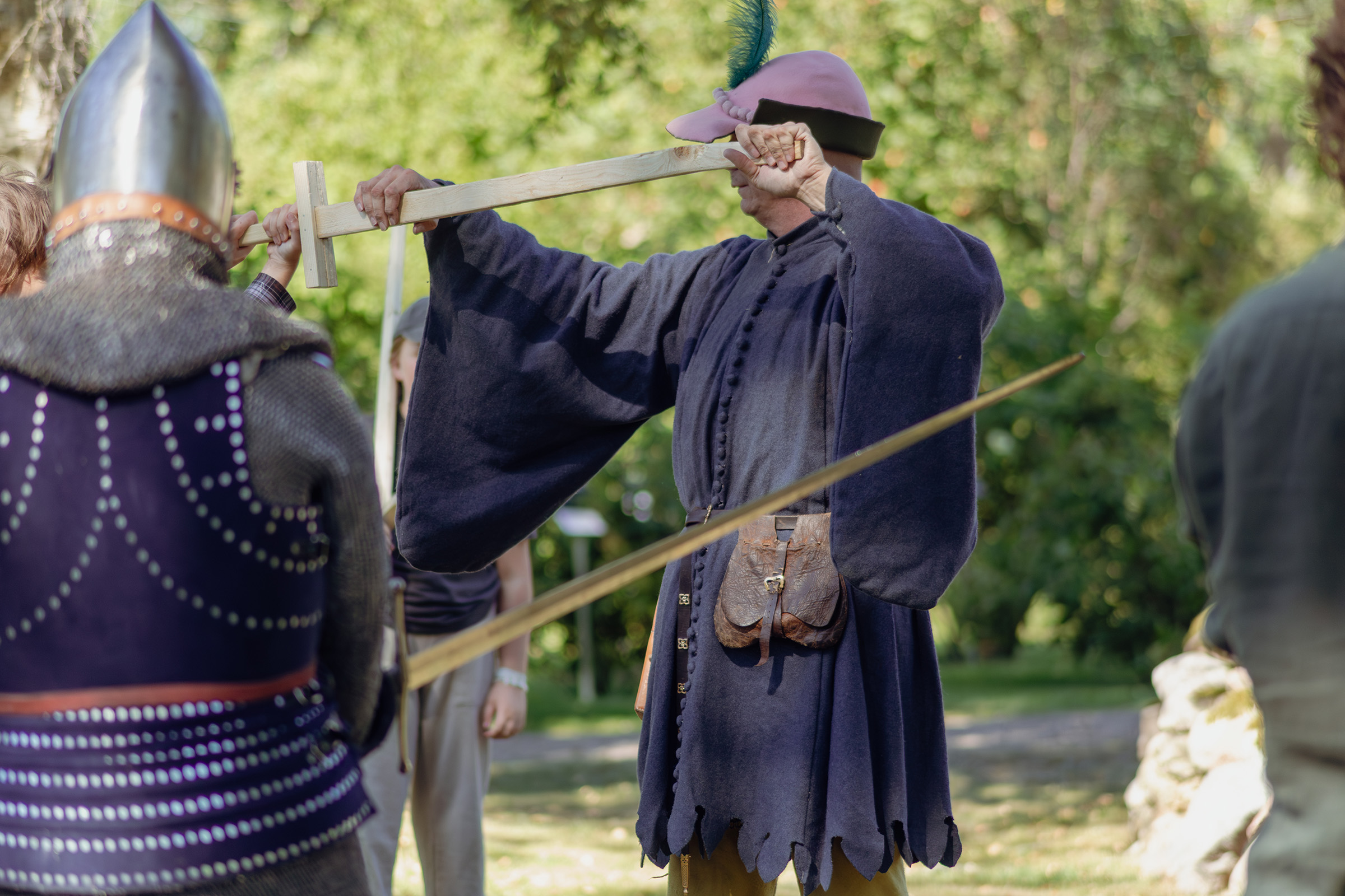 En medeltidsklädd instruktör visar hur ett svärd ska hållas