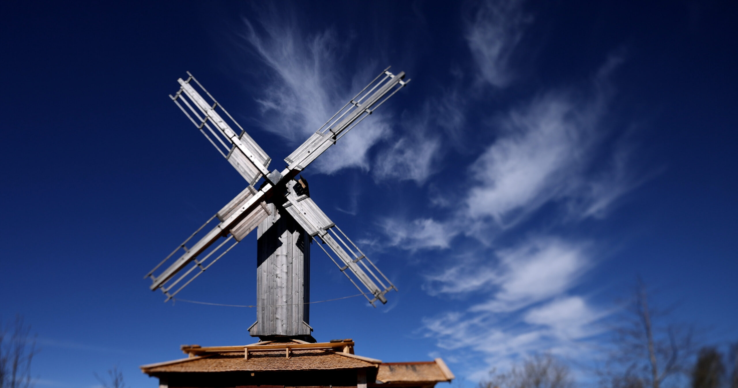 Vy mot en holkkvarns vingar med blå himmel och moln bakom